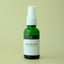 Green spray bottle labeled 'Heatshield Mist' on a beige background