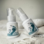Two bottles of  Foot Care products on a textured surface with a neutral background.